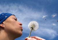 Letting go and feeling peacful - woman blowing dandelion